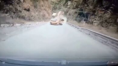 Bagr řítící se proti couvajícímu autu na horské silnici