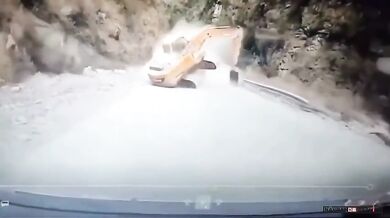 Bagr řítící se proti couvajícímu autu na horské silnici