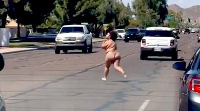 Nahá fackující se žena pobíhající po silnici