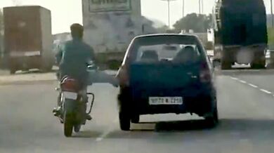 Motorkář tlačí porouchané auto nohou